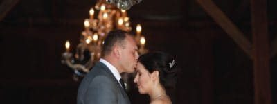 Bride and Groom in a barn with a chandelier embracing one another